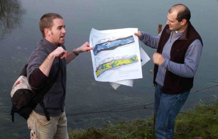 Photo os 2 people holding up a map to show people